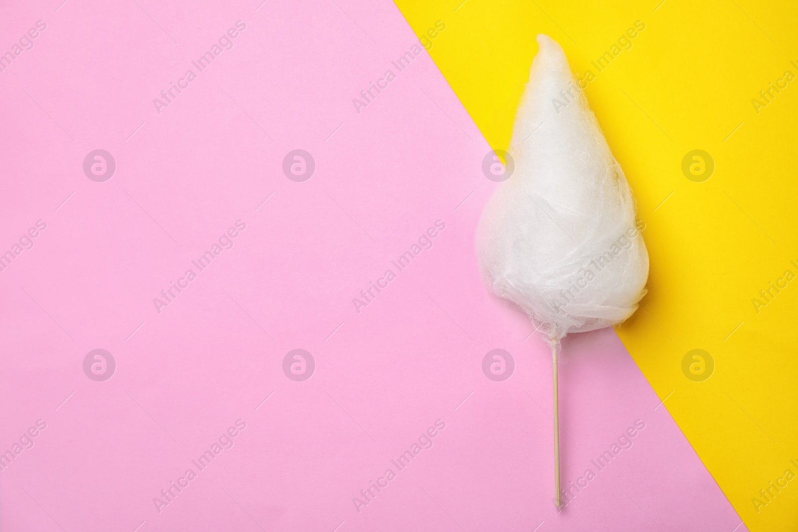 Photo of Stick with yummy cotton candy on color background, top view. Space for text