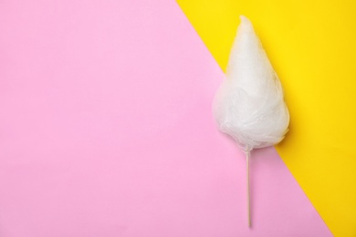 Photo of Stick with yummy cotton candy on color background, top view. Space for text