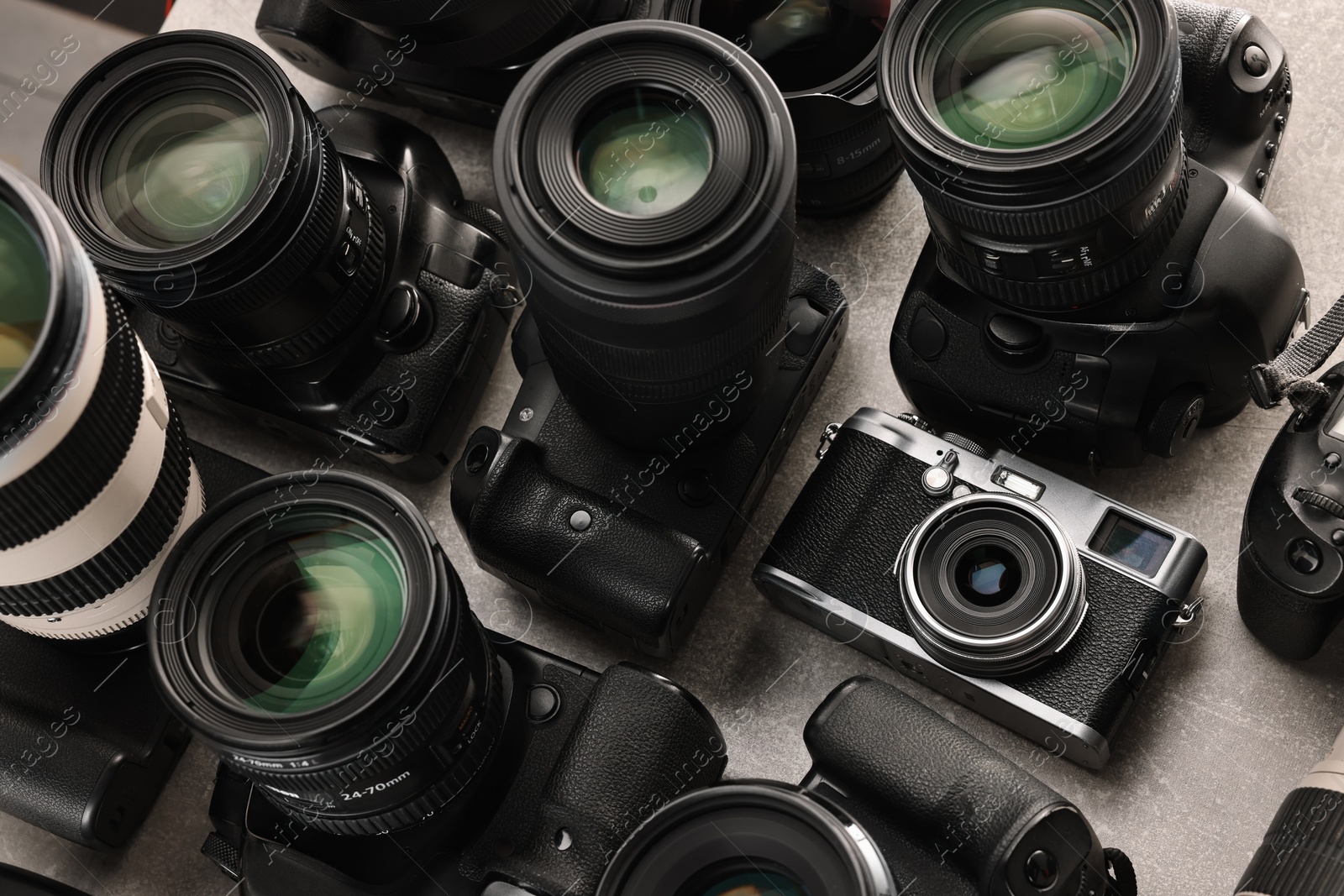 Photo of Modern cameras on gray table, closeup. Professional photography equipment