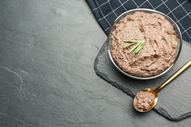 Photo of Tasty liver pate with rosemary on black table, flat lay. Space for text