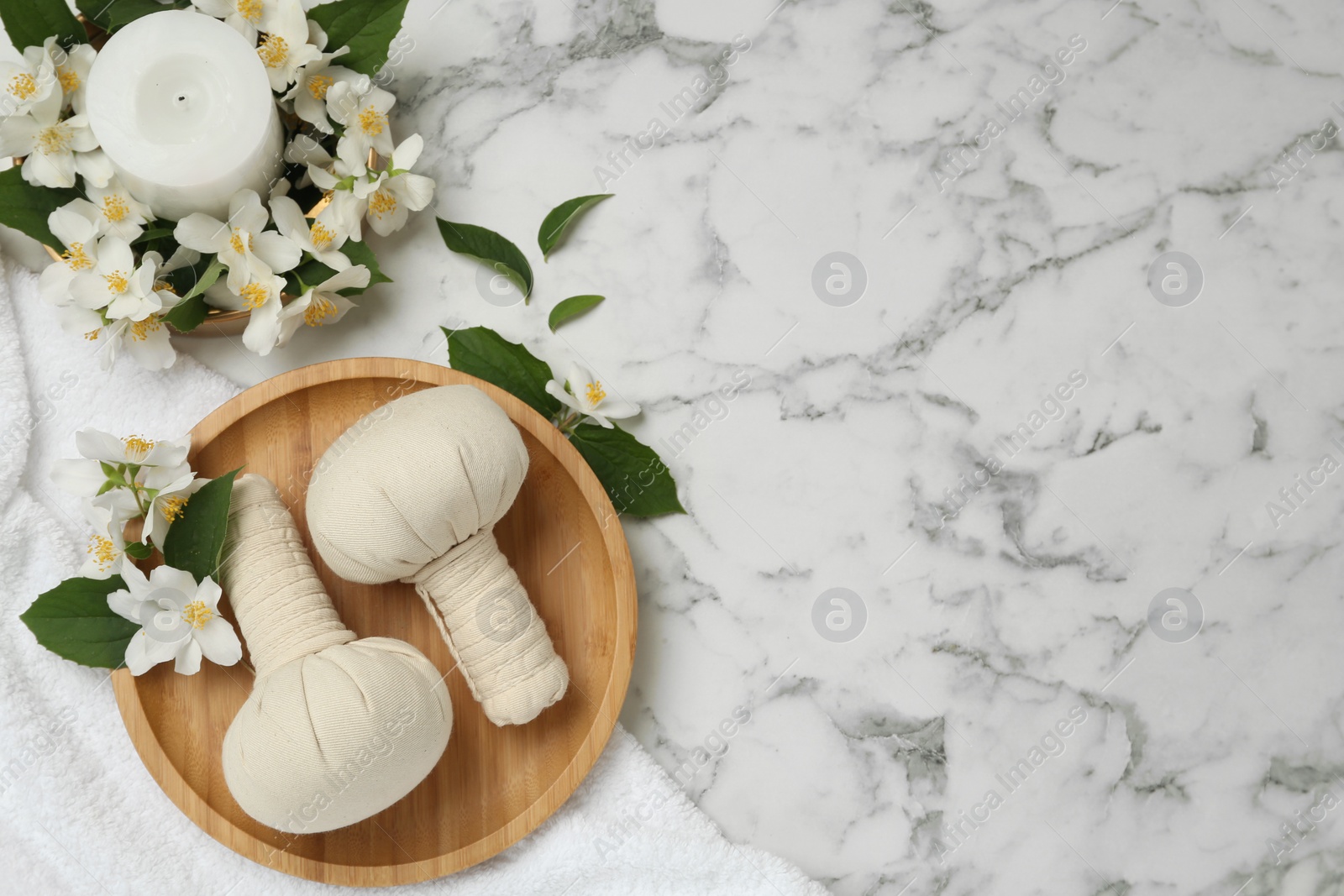 Photo of Beautiful jasmine flowers, herbal bags and candle on white marble table, flat lay. Space for text