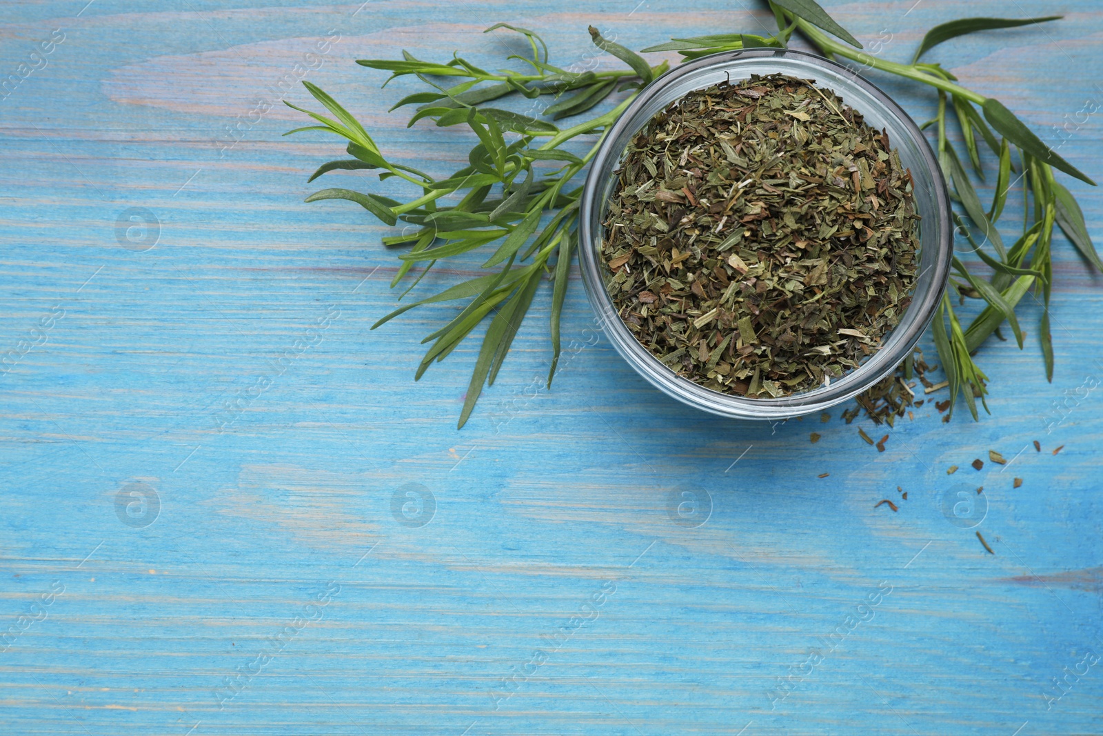 Photo of Dry and fresh tarragon on light blue wooden table, flat lay. Space for text