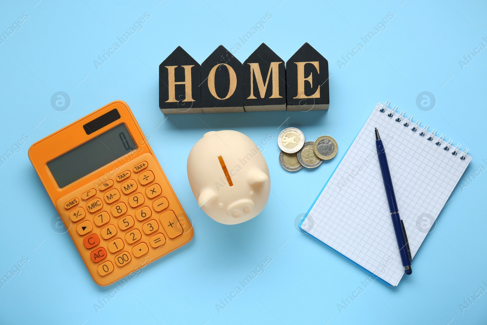 Photo of Flat lay composition with piggy bank and word Home made in shape of houses on light blue background