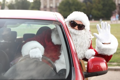 Photo of Authentic Santa Claus with sunglasses driving car, view from outside