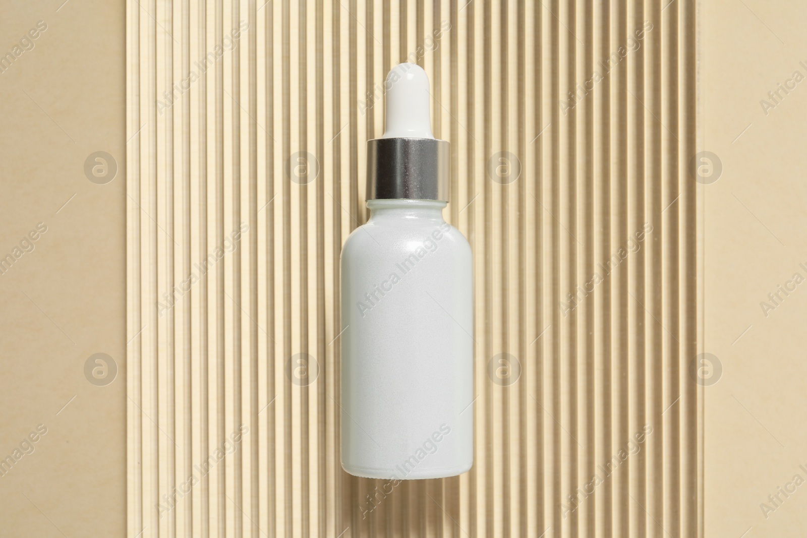 Photo of Bottle of cosmetic serum on beige background, top view