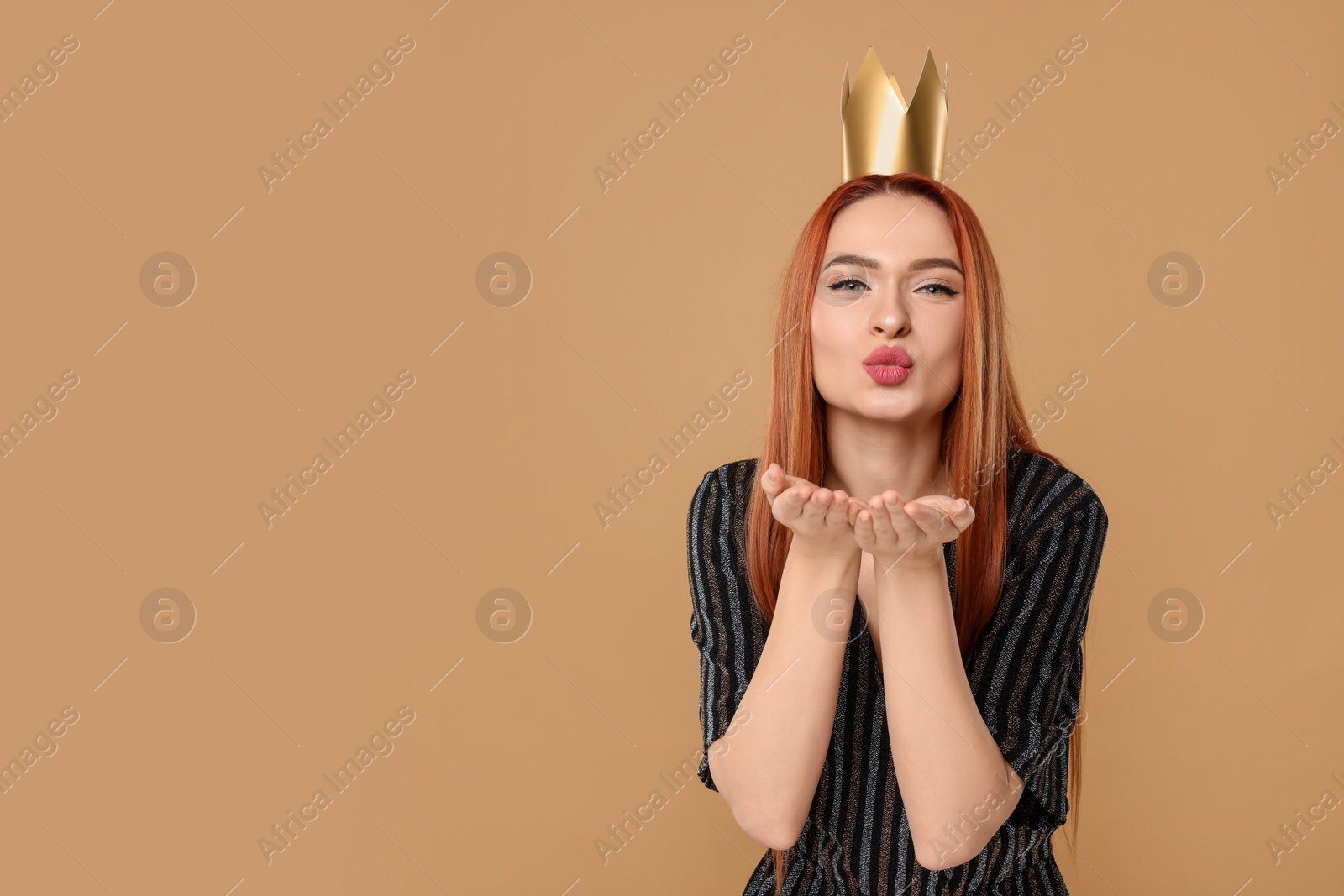 Photo of Beautiful young woman with princess crown blowing kiss on beige background, space for text