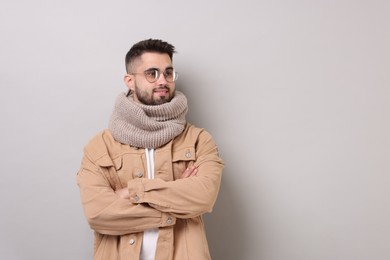 Photo of Smiling man in warm scarf on light grey background. Space for text