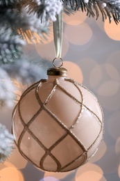 Photo of Christmas tree decorated with holiday ball against blurred lights, closeup