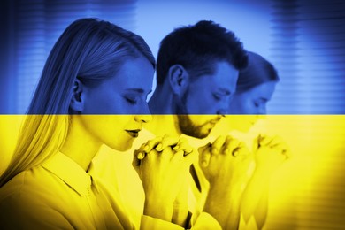 Pray for Ukraine. Double exposure of people praying together and Ukrainian national flag