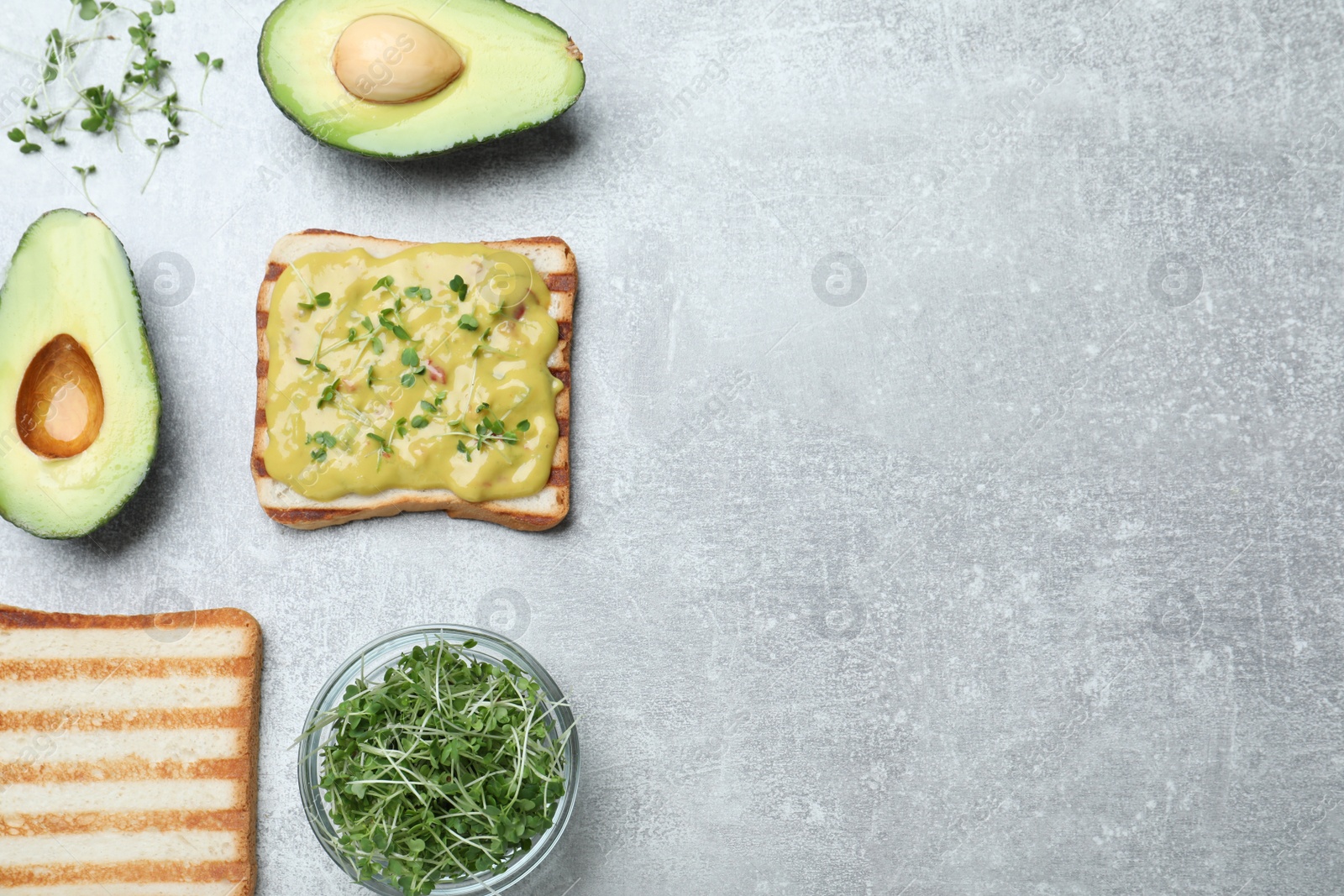 Photo of Delicious sandwich with guacamole and microgreens on grey table, flat lay. Space for text