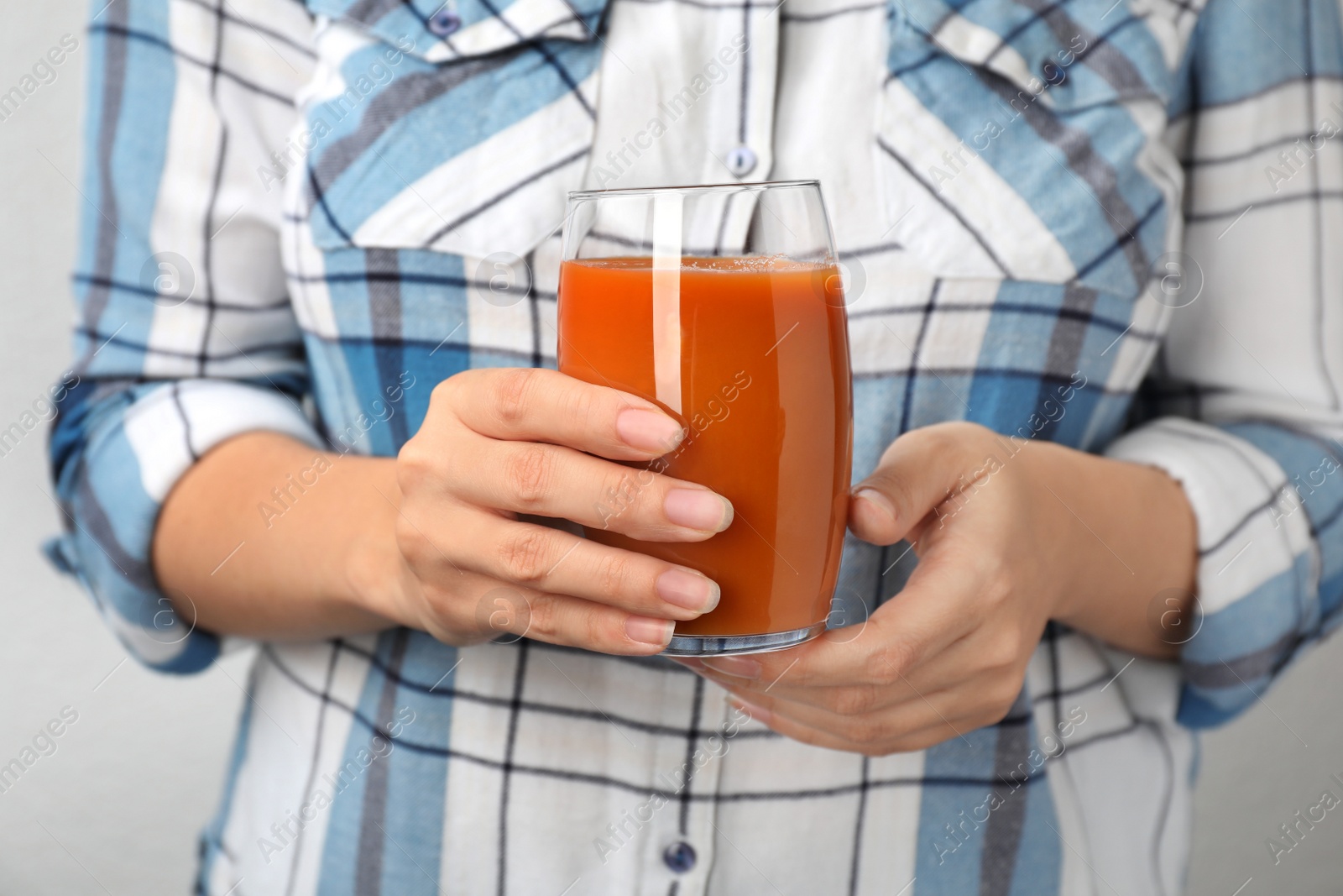 Photo of Woman holding glass of tasty carrot juice, closeup
