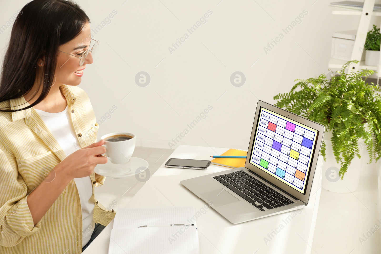 Photo of Young woman using calendar app on laptop in office