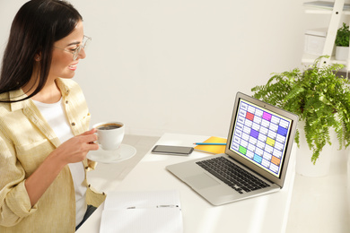 Photo of Young woman using calendar app on laptop in office