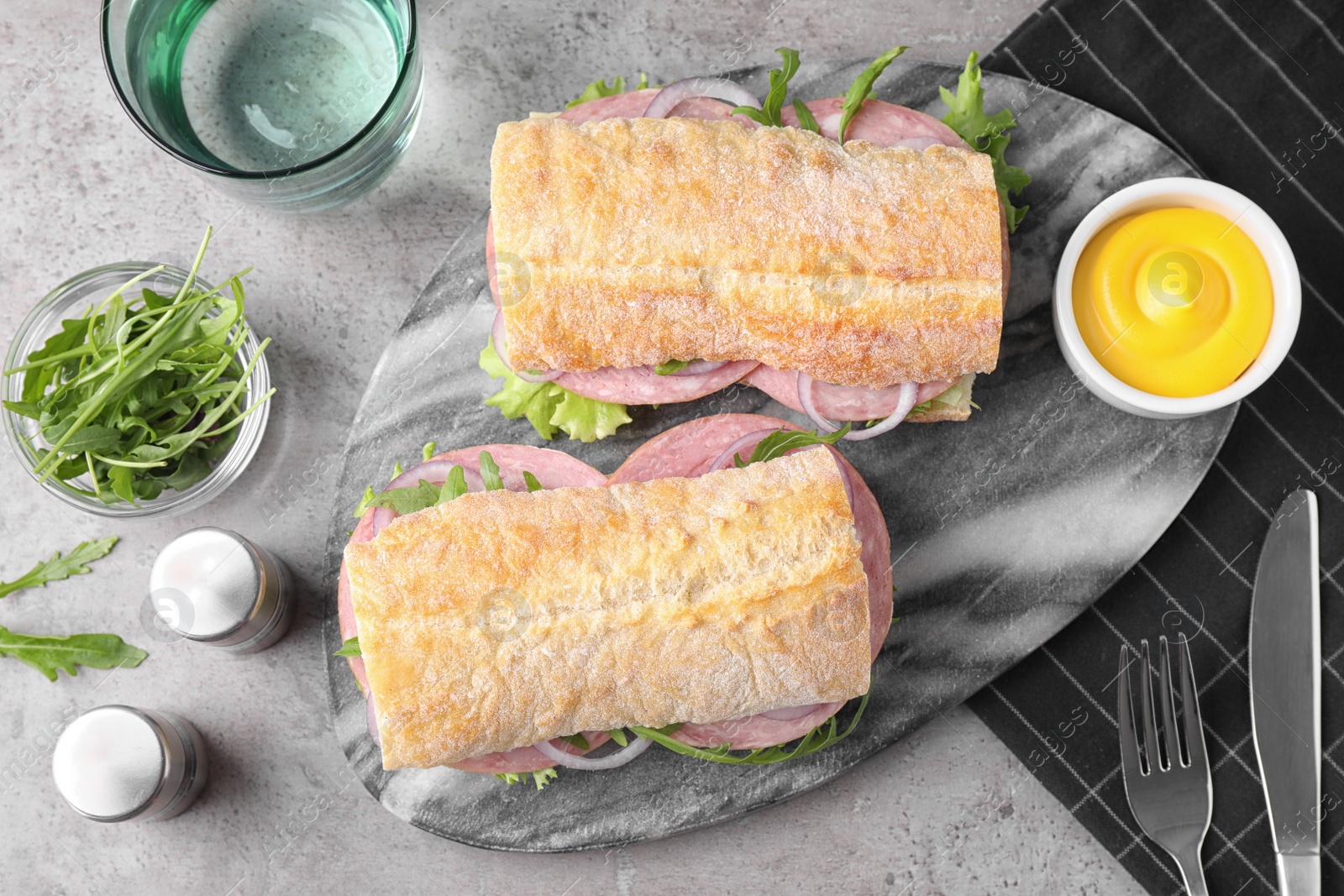 Photo of Tasty sandwiches with ham served on grey table, flat lay