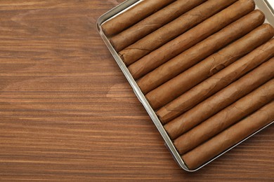 Photo of Box with expensive cigars on wooden table, top view. Space for text