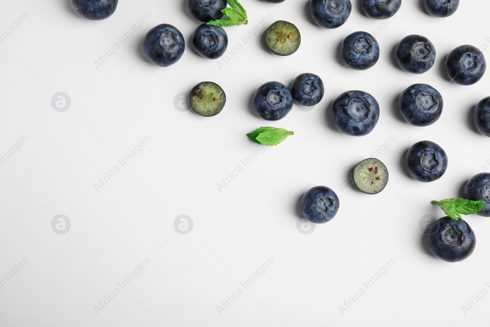 Photo of Tasty ripe blueberries and leaves on white background, flat lay