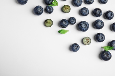 Tasty ripe blueberries and leaves on white background, flat lay