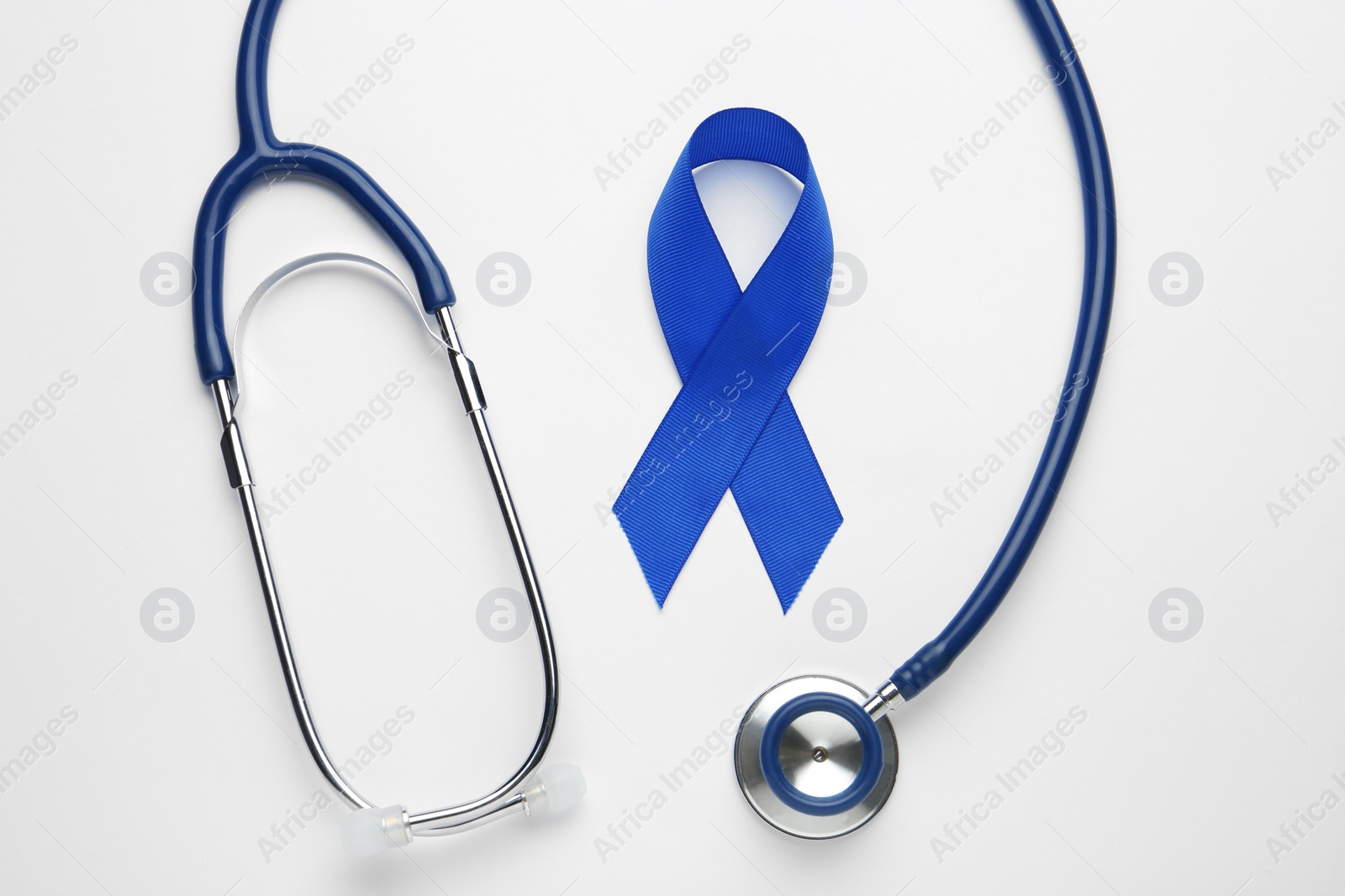 Photo of Blue awareness ribbon and stethoscope isolated on white, top view. Symbol of medical issues