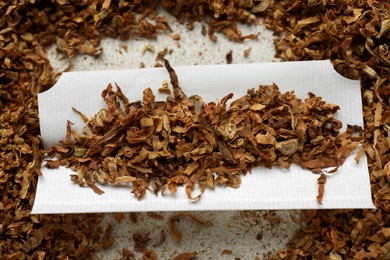 Photo of Paper and tobacco on light grey table, closeup. Making hand rolled cigarette