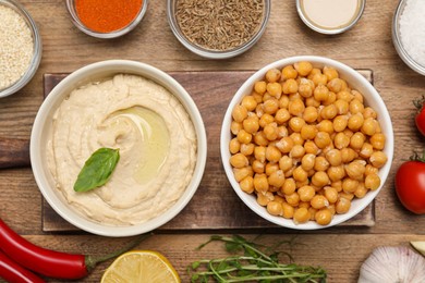 Photo of Bowl with delicious hummus and different ingredients on wooden table, flat lay