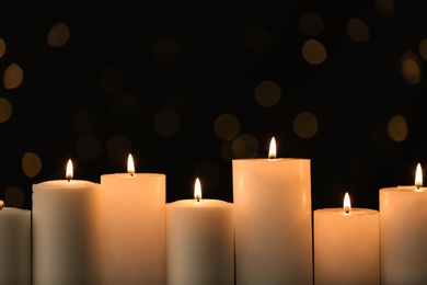 Burning candles on black background with blurred lights