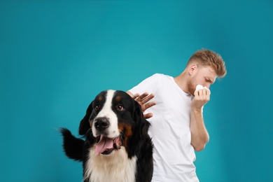 Young man suffering from fur allergy on blue background