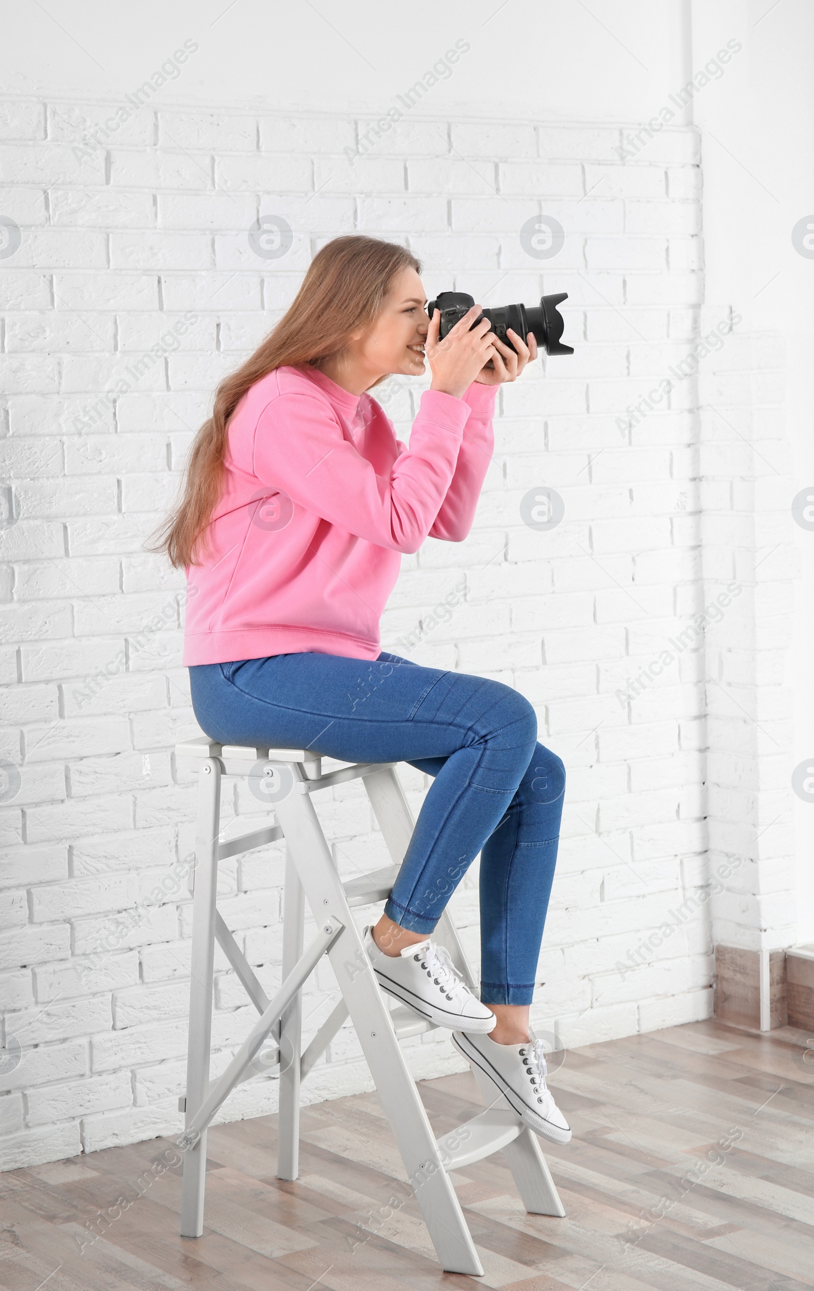 Photo of Female photographer with camera sitting on chair indoors