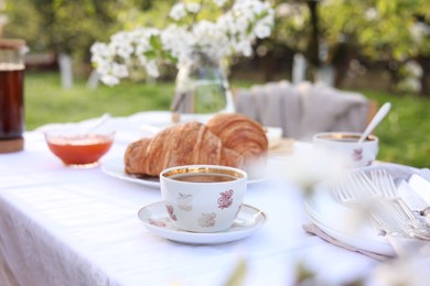 Photo of Stylish table setting with tea and croissants in spring garden