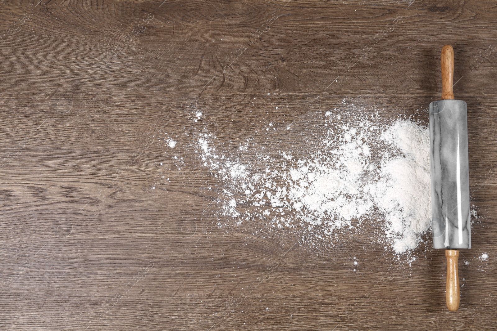 Photo of Flour and rolling pin on wooden table, flat lay