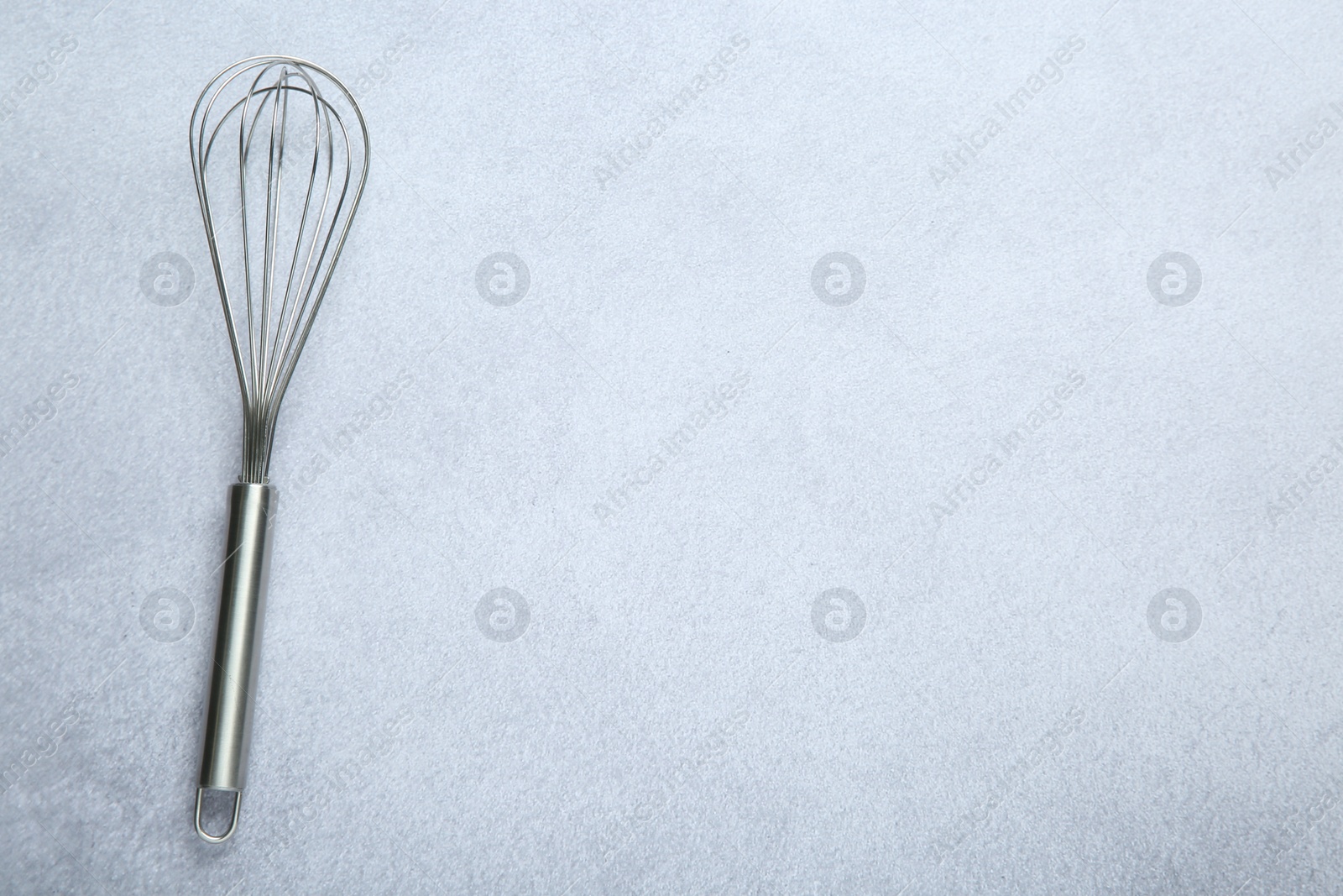 Photo of Metal whisk on gray table, top view. Space for text