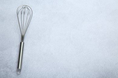 Photo of Metal whisk on gray table, top view. Space for text