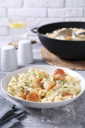 Photo of Delicious scallop pasta with spices in bowl on gray textured table