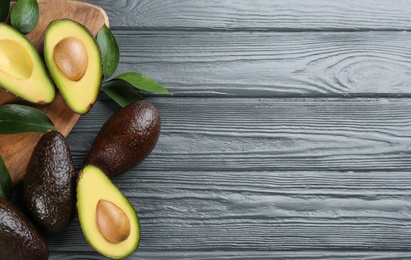 Photo of Whole and cut avocados on grey wooden table, flat lay. Space for text