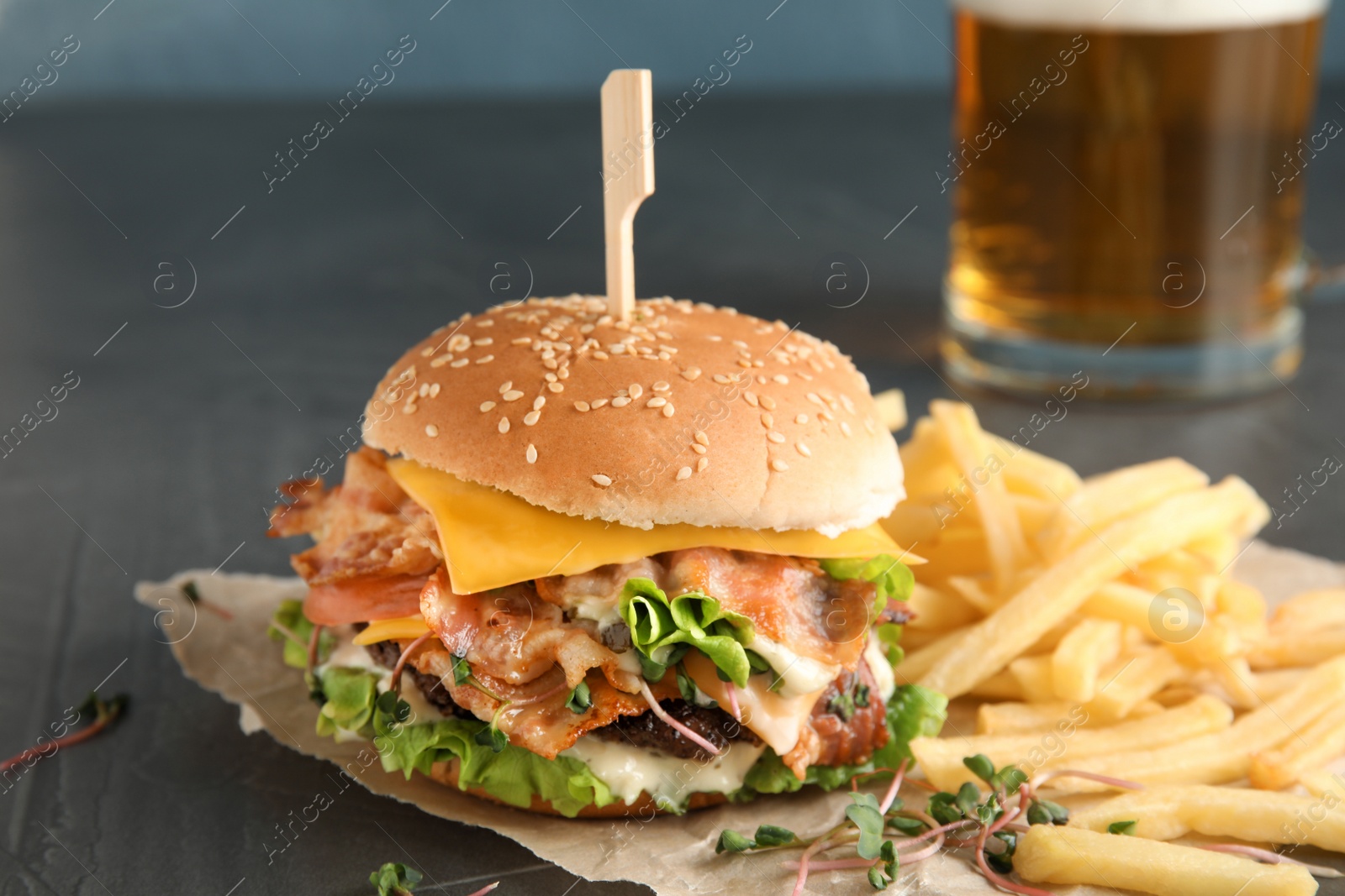 Photo of Tasty burger with bacon and French fries on table