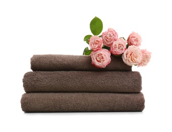 Stack of clean folded towels with flowers on white background