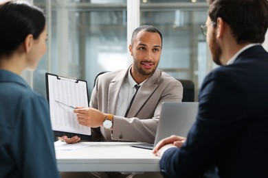 Photo of Lawyer with clipboard working with clients at table in office