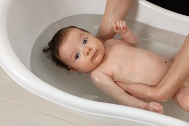 Mother bathing her little baby in bathtub, closeup