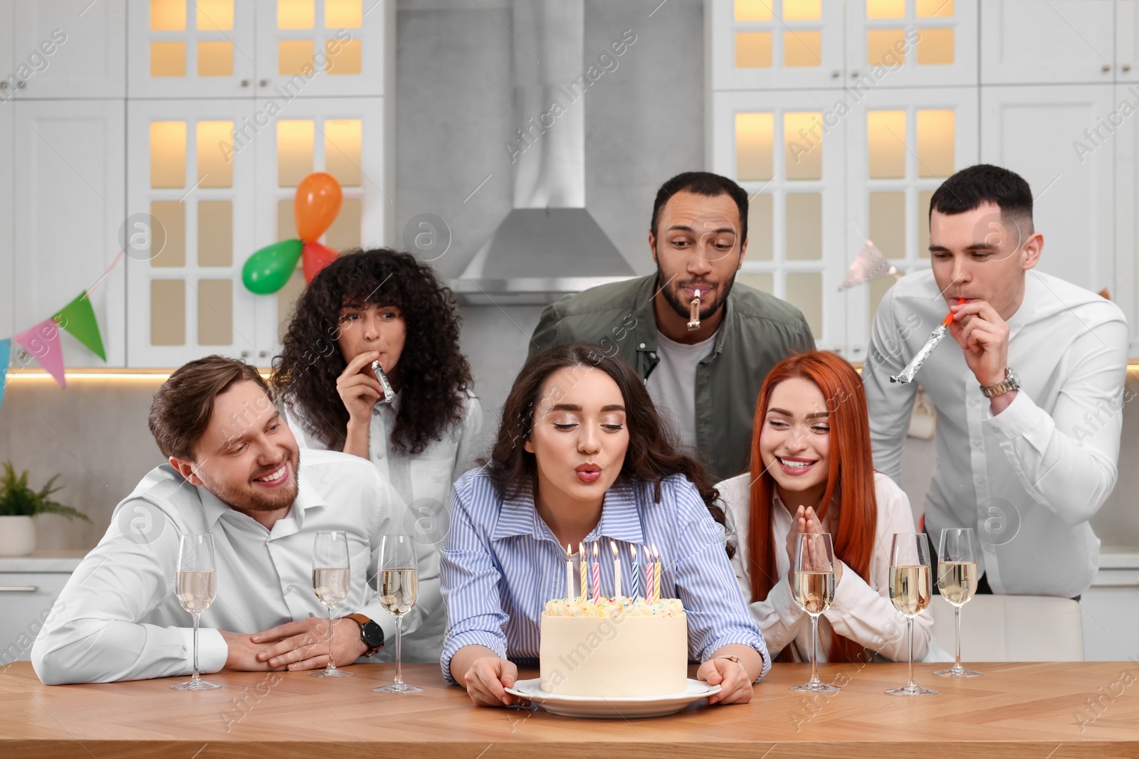 Photo of Happy friends with tasty cake celebrating birthday in kitchen