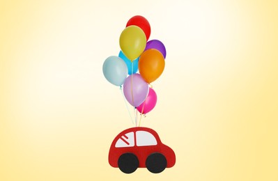 Image of Many balloons tied to toy car flying on golden background