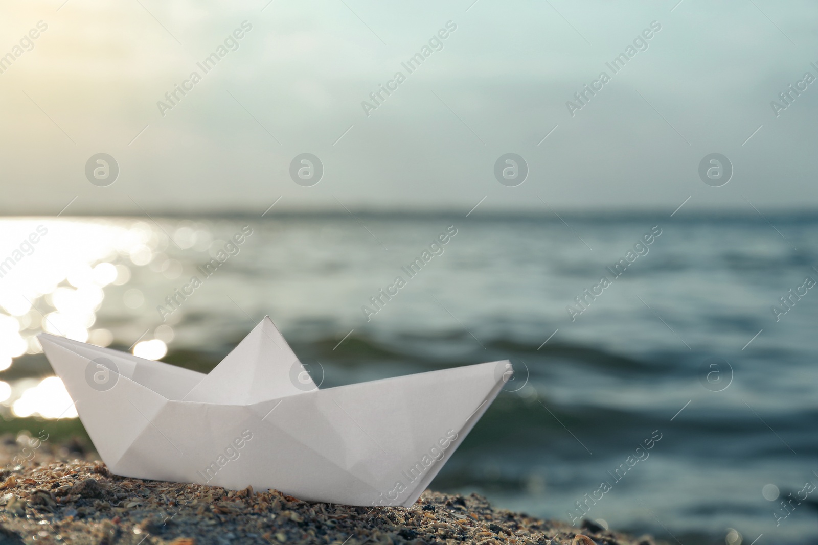 Photo of White paper boat near river on sunny day, space for text