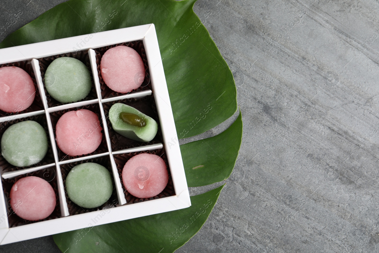 Photo of Box with different delicious mochi on grey table, top view. Space for text