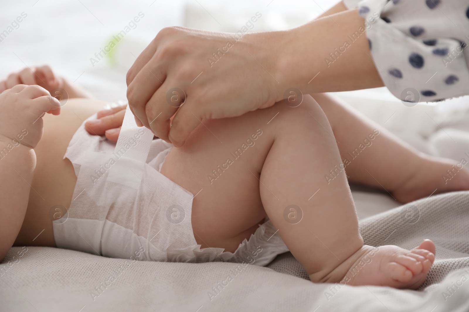 Photo of Mother changing her baby's diaper on bed, closeup