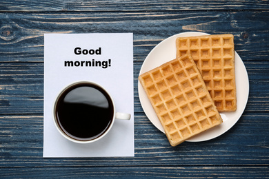 Photo of Coffee with wafers for breakfast and Good Morning wish on blue wooden table, flat lay