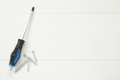 Photo of Screwdriver with black handle and screws on white wooden table, flat lay. Space for text