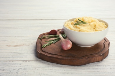 Photo of Bowl with mashed potatoes on wooden board. Space for text