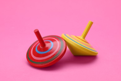 Photo of Two bright spinning tops on pink background. Toy whirligig