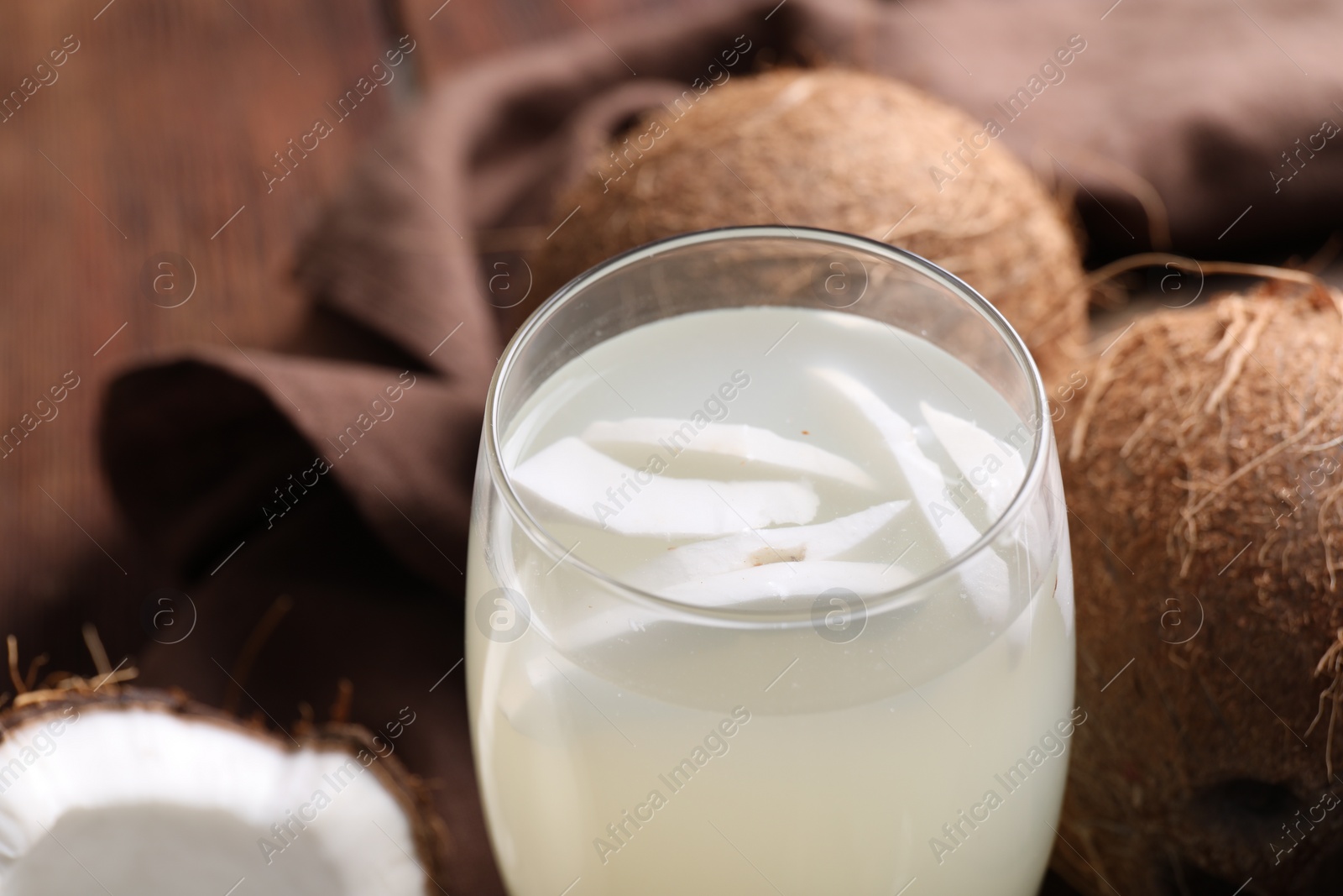 Photo of Glass of coconut water and nuts on table, closeup