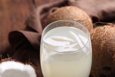 Glass of coconut water and nuts on table, closeup