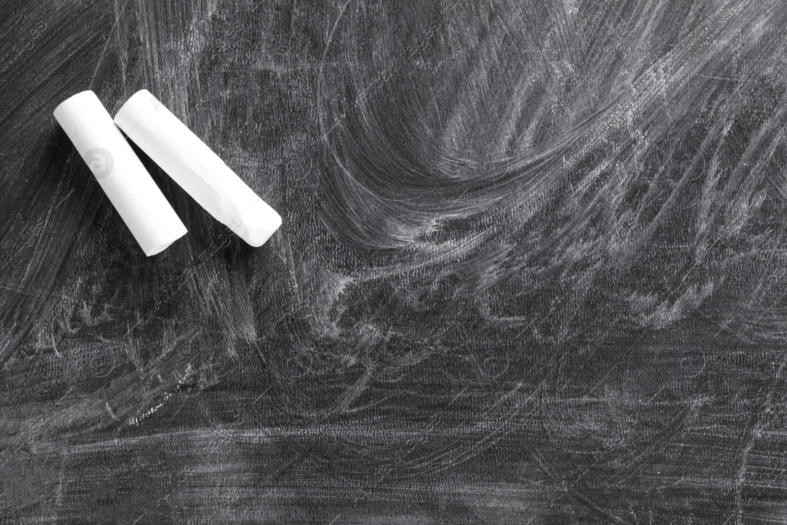 Photo of Pieces of white chalk on blackboard, flat lay. Space for text