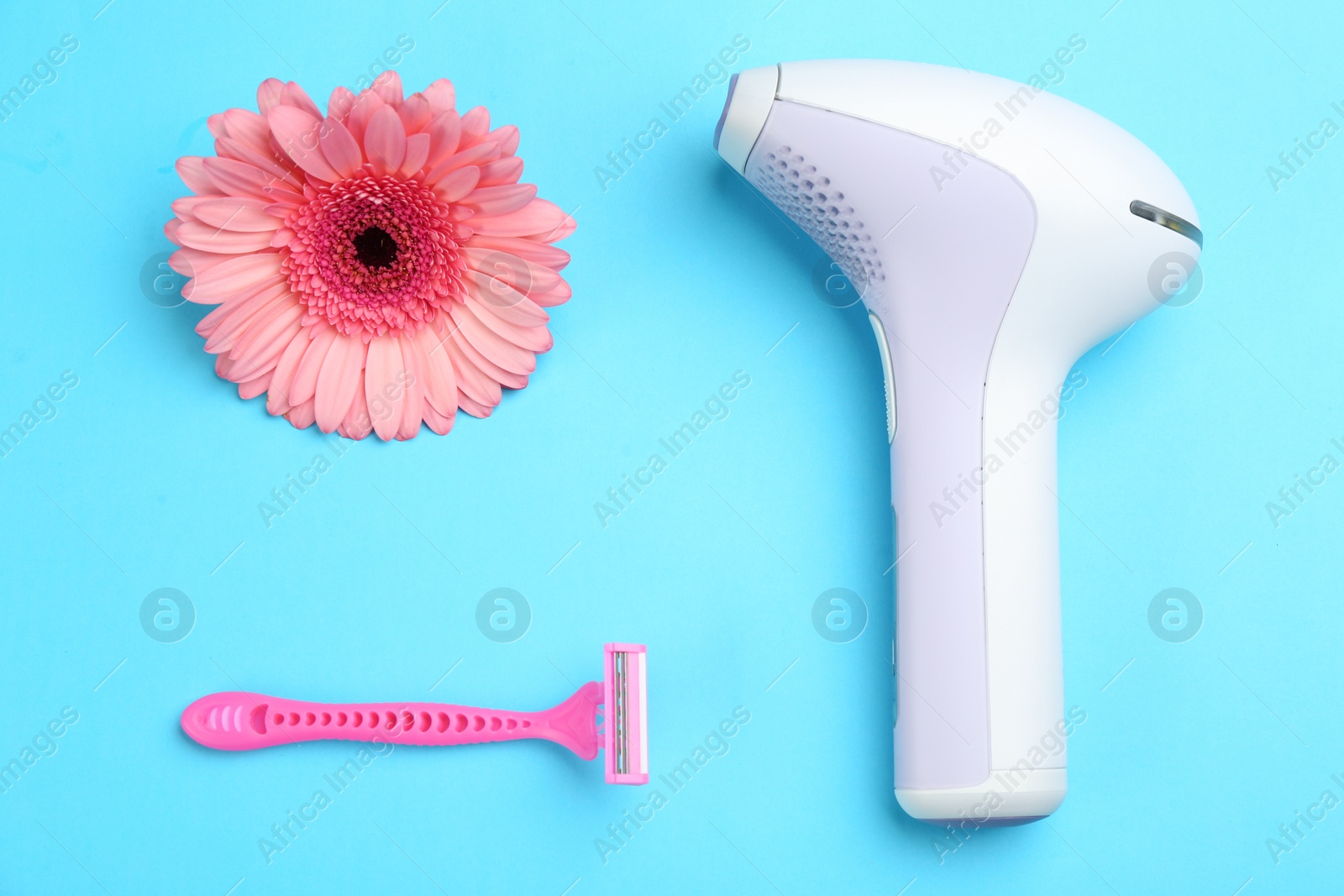 Photo of Modern photoepilator, razor and flower on blue background, flat lay